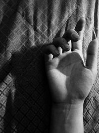 Cropped hand of woman on bed at home