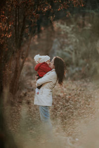 Mother carrying toddler daughter at park