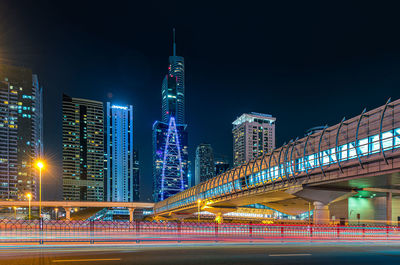 Illuminated modern buildings in city against sky at night