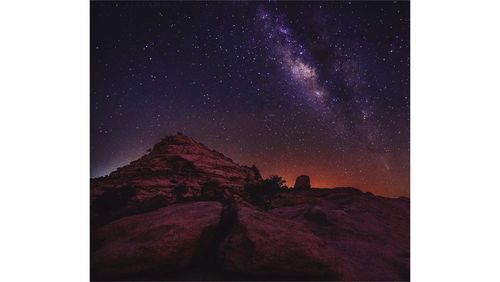 Low angle view of rocks against star field in sky at night