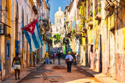 People in alley amidst buildings during sunny day