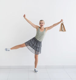 Full length portrait of a smiling young woman over white background