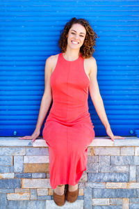 Portrait of young woman standing against wall