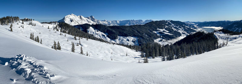 Panorama of snow covered mountains in saalbach hinterglemm in the austrian alps against blue sky