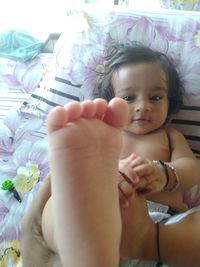 Portrait of cute baby girl on bed at home