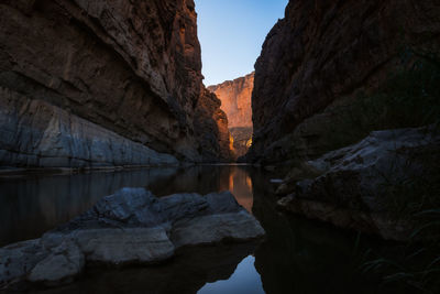 Rock formations by lake against sky