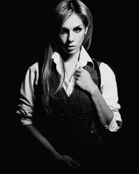 Portrait of young female model wearing waistcoat against black background