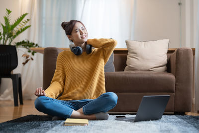 Portrait of young woman using mobile phone while sitting on sofa at home