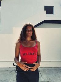 Portrait of young woman standing against wall