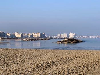 Sea and buildings against clear sky