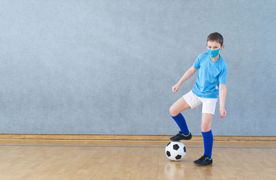 Portrait of boy wearing mask playing soccer