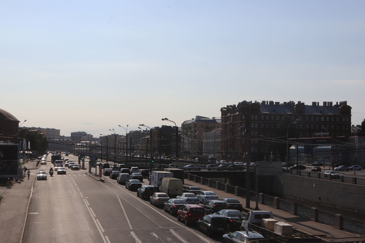 TRAFFIC ON ROAD AMIDST BUILDINGS AGAINST SKY IN CITY