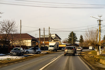 Cars on street by buildings in city against sky