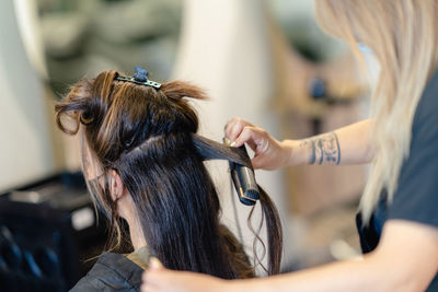 Midsection of hairdresser grooming customer in salon