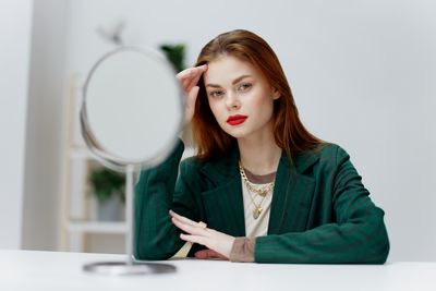 Portrait of young woman using mobile phone while sitting against white background