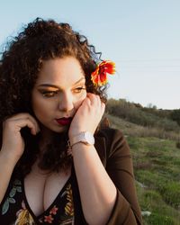 Portrait of beautiful young woman holding flower in field