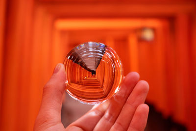 Cropped hand holding crystal ball against empty corridor