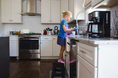 Little girl at sink washing dishes