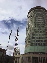 Low angle view of modern building against cloudy sky