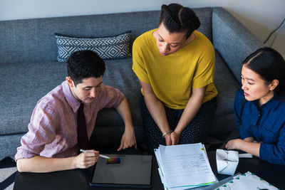 Businessman showing graphics tablet to female colleagues while planning in meeting at office