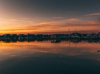 Scenic view of river by buildings against sky during sunset