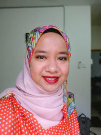 Portrait of happy woman wearing hijab at home