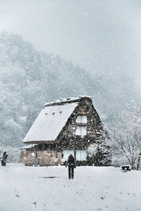 Man walking on snow covered house by building