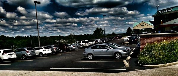 Cars moving on road against cloudy sky