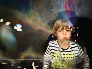 Boy playing with bubbles standing at railing