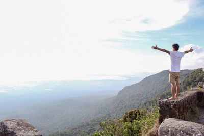 Man with arms outstretched standing on rock