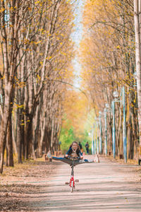 Woman on road amidst trees in forest during autumn