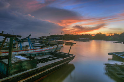 Boats moored in lake against sky during sunset