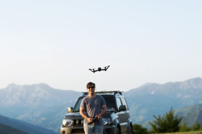 Young man flying over mountains against clear sky