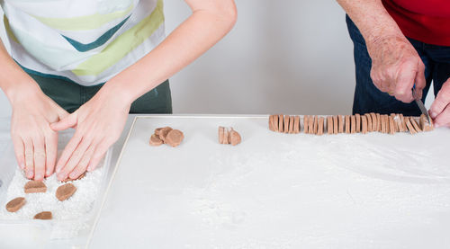 Midsection of people making cookies on table at home