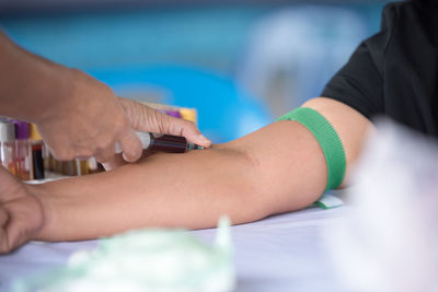 Cropped hands of nurse removing blood from patient arm in hospital