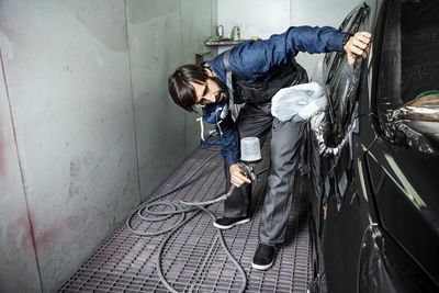 Man painting car in factory