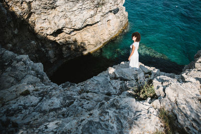 Woman standing on rock by sea