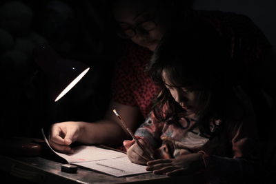 Close-up of mother teaching daughter at home