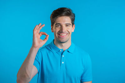 Portrait of smiling man standing against blue background