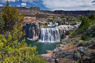 Scenic view of waterfall against sky