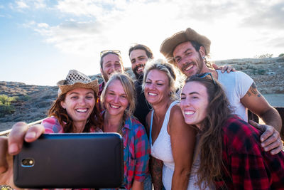 Portrait of smiling young woman using smart phone against sky