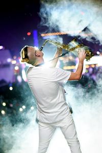 Rear view of man playing trumpet on music concert