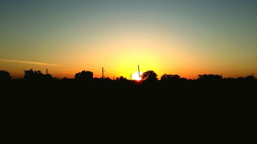 Silhouette trees against orange sky