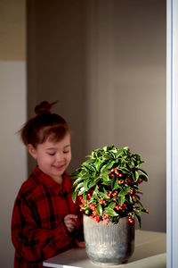 Portrait of cute girl looking at potted plant