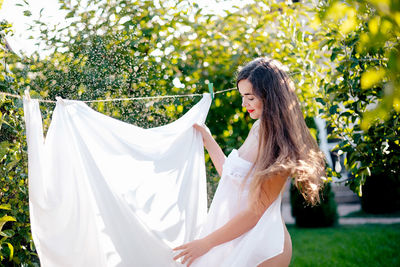 Portrait of smiling young woman standing against plants