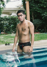 Portrait of shirtless man standing in pool