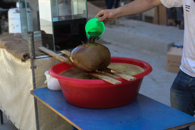 Midsection of man pouring liquid on food