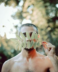 Man with blue eyes hiding behind leaves