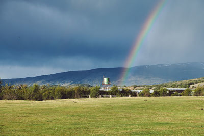 Scenic view of rainbow over field against sky