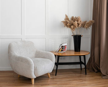 A gray armchair and a coffee table stand on a wooden floor against a white wall.